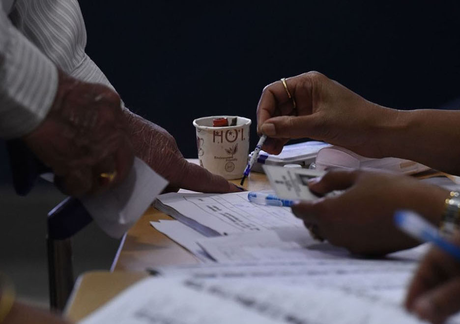 ووٹ دالنے کے بعد ہر ووٹر کے بائیں ہاتھ کی شہادت کی انگلی پر اَنمٹ سیاہی لگائی جارہی ہے۔ تصویر: اے ایف پی